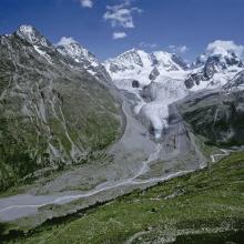 Proglacial margin of Vadret da Roseg, crossed by a brook. In the background, the Roseg glacier and the Bernina massif.